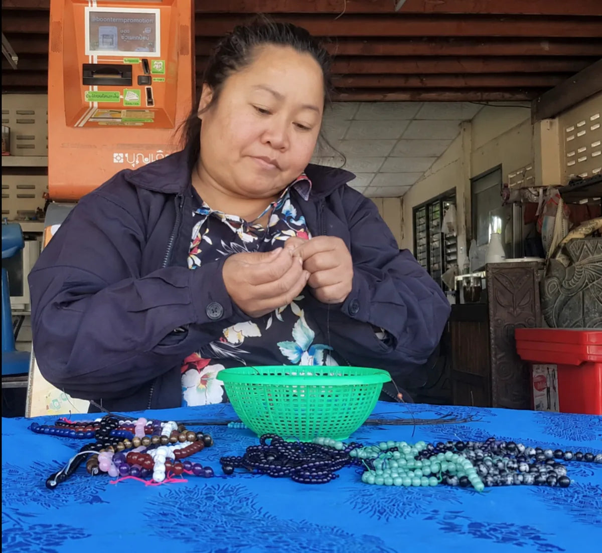 Une artisane assemble des bracelets de perles à sa table de travail