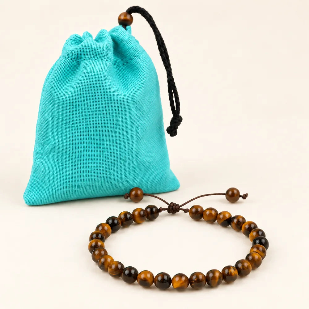 Le bracelet en œil de tigre posé devant son pochon turquoise